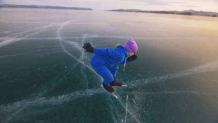 The child train on ice speed skating. The athlete at the start, in a sports stance. The kid girl skates in the winter in sportswear, sport glasses.の写真素材