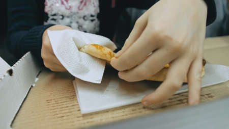 Mother and daughter eat pizza cheese four. Close up of young woman eating pizza and chewing in outdoor restaurant. Girl hands taking pieces pizza.の写真素材