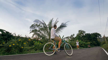 Biking road trip. The man on blue bike in white clothes on forest road. The biker men ride on bicycle. Cycling Cycle Fix. Asia Thailand ride tourism.の写真素材