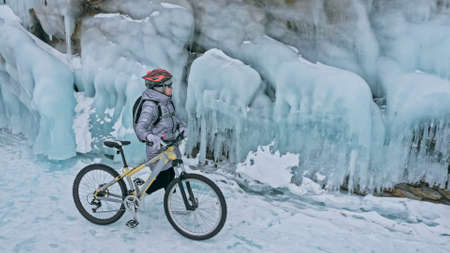 Woman is riding bicycle near the ice grotto. The rock with ice cの写真素材