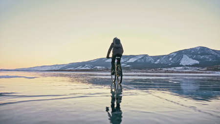 Man is riding bicycle on the ice. Ice of frozen Lake Baikal. Teeの写真素材