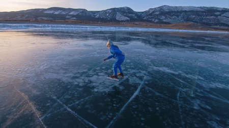 The child train on ice professional speed skating. The girl skates in the winter in sportswear, sport glasses, suit. Outdoor slow motion.の写真素材