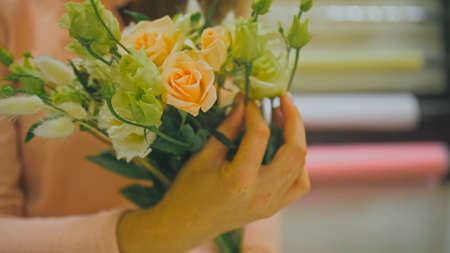 Female florist makes flower bunch, she cuts off wrapping paper wの写真素材