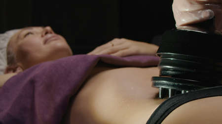 Young caucasian woman receiving anti-fat anti-cellulite professional vibration massage and relax in...