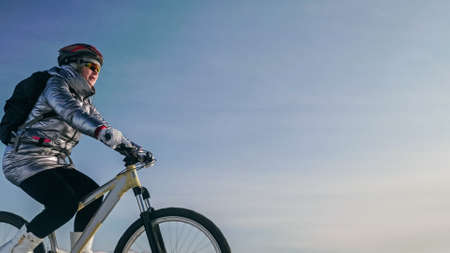 Woman is riding bicycle on the ice. Tires on bike are covered wiの写真素材