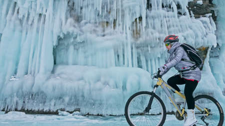 Woman is riding bicycle near the ice grotto. The rock with ice cの写真素材