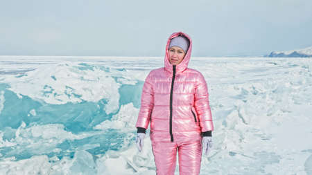Girl walking on cracked ice of a frozen lake Baikal. Woman traveの写真素材