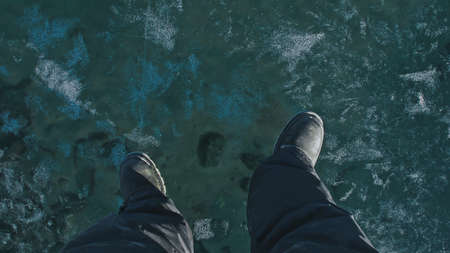 A man walks on frozen Lake Baikal with blue transparent ice withの写真素材