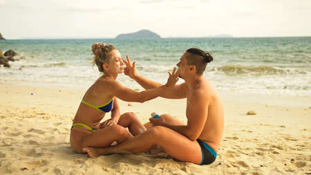 Cute loving couple each other having sun block. Woman to put sun
