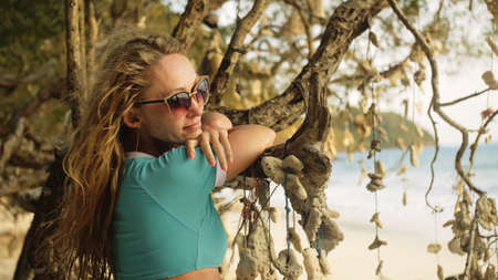 Woman walking alone on beach and relax among the tree hung withの写真素材