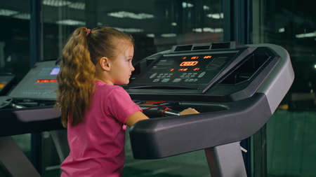 Fit Athletic Baby Girl Running on the Treadmill, Doing Her Fitness Exercise. Cute Children Actively...