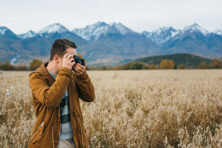 The man is a photographer in the field takes a picture on an old retro film camera.の写真素材
