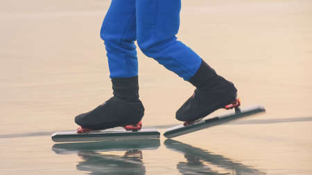 The child train on ice speed skating. The legs in skates close up. The kid girl skates in the winter...