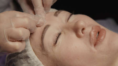 Woman receiving anti-ageing facial massage in spa salon relax. Wellness body skin care face beauty treatment. Black backgroundの写真素材