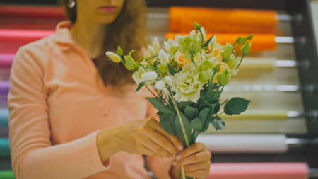 Female florist makes flower bunch, she cuts off wrapping paper wの写真素材