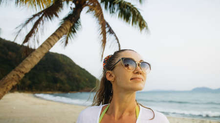 Close up portrait woman in a white tunic shirt on beach, near st