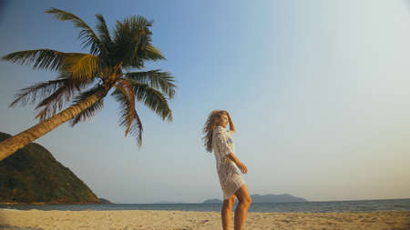 Woman in a White Tunic on Beach, near the Sea, Palm Tree. Blonde