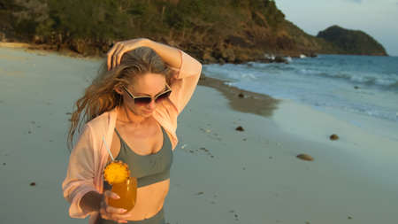 Woman walks on sunset on beach against background of sea. Girl i