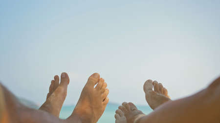 Barefoot young man and woman rest lying on beach near ocean