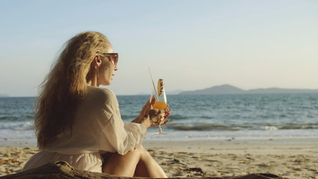 Woman sitting in white dress drinks pineapple cocktail Pina Colaの写真素材