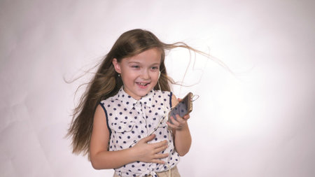 Child with headphones dancing at studio background. Girl listens to music on smartphone. Beautiful cute happy little girl listens to music.の写真素材