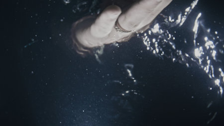 With the palm of your hand, check or mix the water. Bottom view from under the water. Divine god hand. A finger is wearing a ring. Black background.の写真素材
