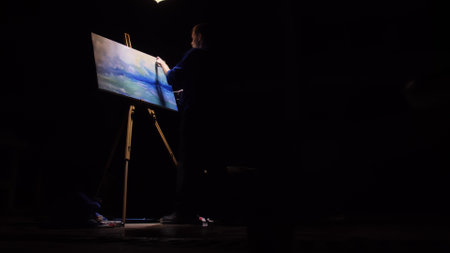 Artist copyist paint seascape with ship in ocean. Craftsman decorator draw as boat sail on blue sea. Black background. Wide angle shot.の写真素材