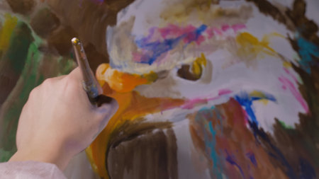 Artist designer draws an eagle on the wall. Craftsman decorator paints a picture with acrylic oil color. Close-up dark magic cinematic look.の写真素材