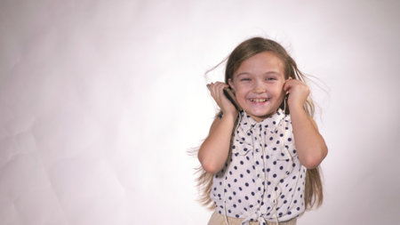 Child with headphones dancing at studio background. Girl listens to music on smartphone. Beautiful cute happy little girl listens to music.の写真素材