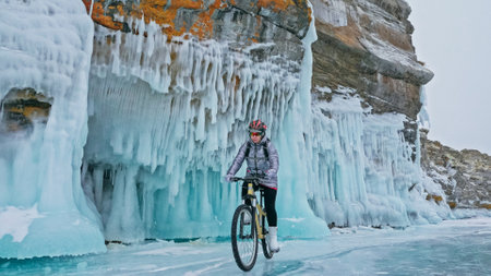 Woman is riding bicycle near the ice grotto. The rock with ice cの写真素材