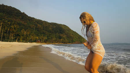 Woman in a white tunic on the beach, near the stormy sea. Blonde