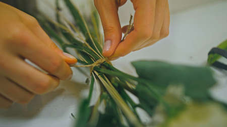 Female florist makes flower bunch, she cuts off wrapping paper wの写真素材