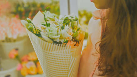 Female florist makes flower bunch, she cuts off wrapping paper wの写真素材