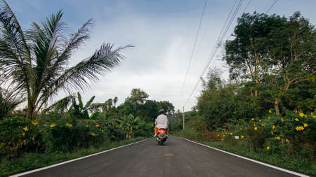 Love couple on red motorbike in white clothes to go on forest road trail trip. Two caucasian tourist...