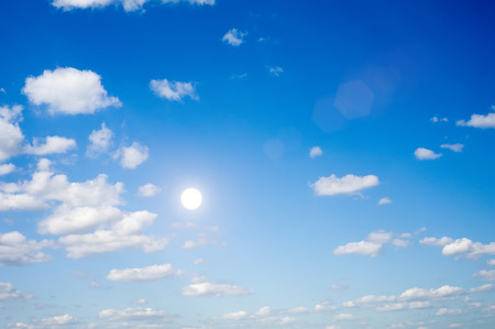 In the dark blue sky the sun and white clouds.の写真素材