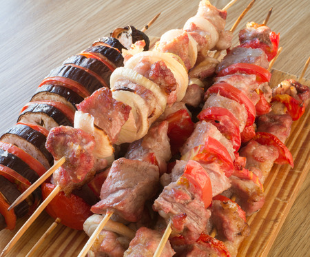 on a table lie the prepared meat on skewers and a baked eggplantの写真素材