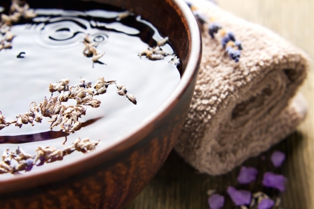 Bowl of pure water and lavender petals on the old wooden surface  Spa treatments compositionの写真素材
