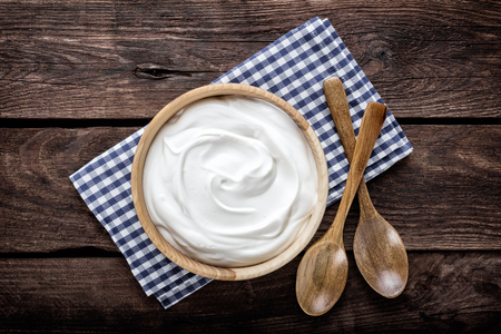 sour cream in wooden bowl top view