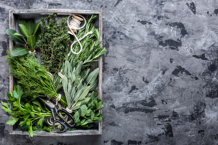 fresh herbs in wooden box on stone background with space for textの写真素材