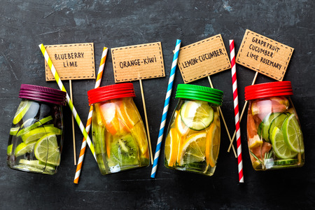 Variety of fruit infused detox water in jars for a healthy diet top view on a dark backgroundの写真素材