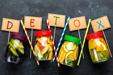Variety of fruit infused detox water in jars for a healthy diet top view on a dark backgroundの写真素材
