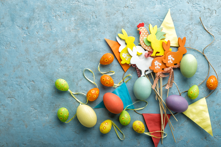 colorful painted Easter eggs and decorations on a light stone background with space for textの写真素材