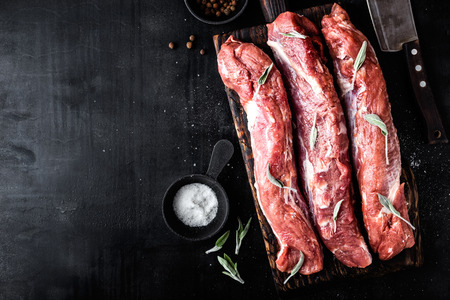 fresh raw pork tenderloin on wooden cutting board on dark background and blank space for your textの写真素材