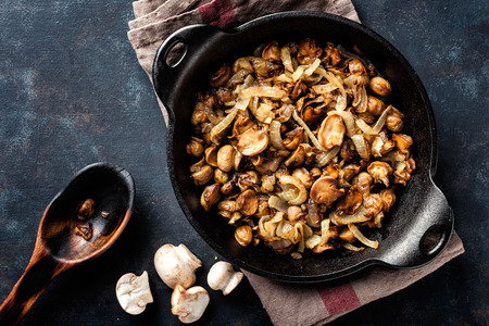 Mushrooms champignon fried with onion in pan, top viewの写真素材