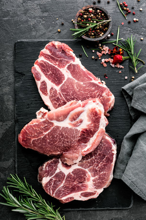Fresh steaks from Raw pork meat on dark stone background, Top viewの写真素材