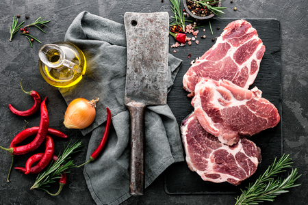 Fresh steaks from Raw pork meat on dark stone background, Top viewの写真素材
