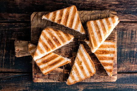 hot toasted sandwich panini with ham and cheese on wooden cutting boardの写真素材