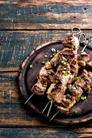 Grilled meat skewers, shish kebab on wooden background, top viewの写真素材
