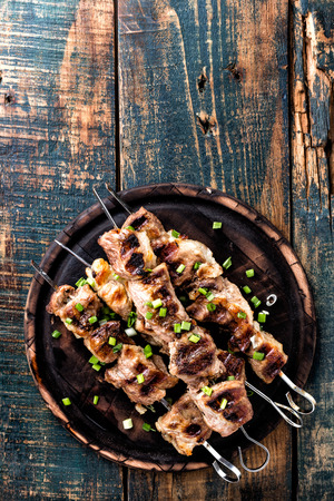 Grilled meat skewers, shish kebab on wooden background, top viewの写真素材