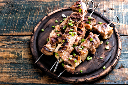 Grilled meat skewers, shish kebab on wooden background, top viewの写真素材